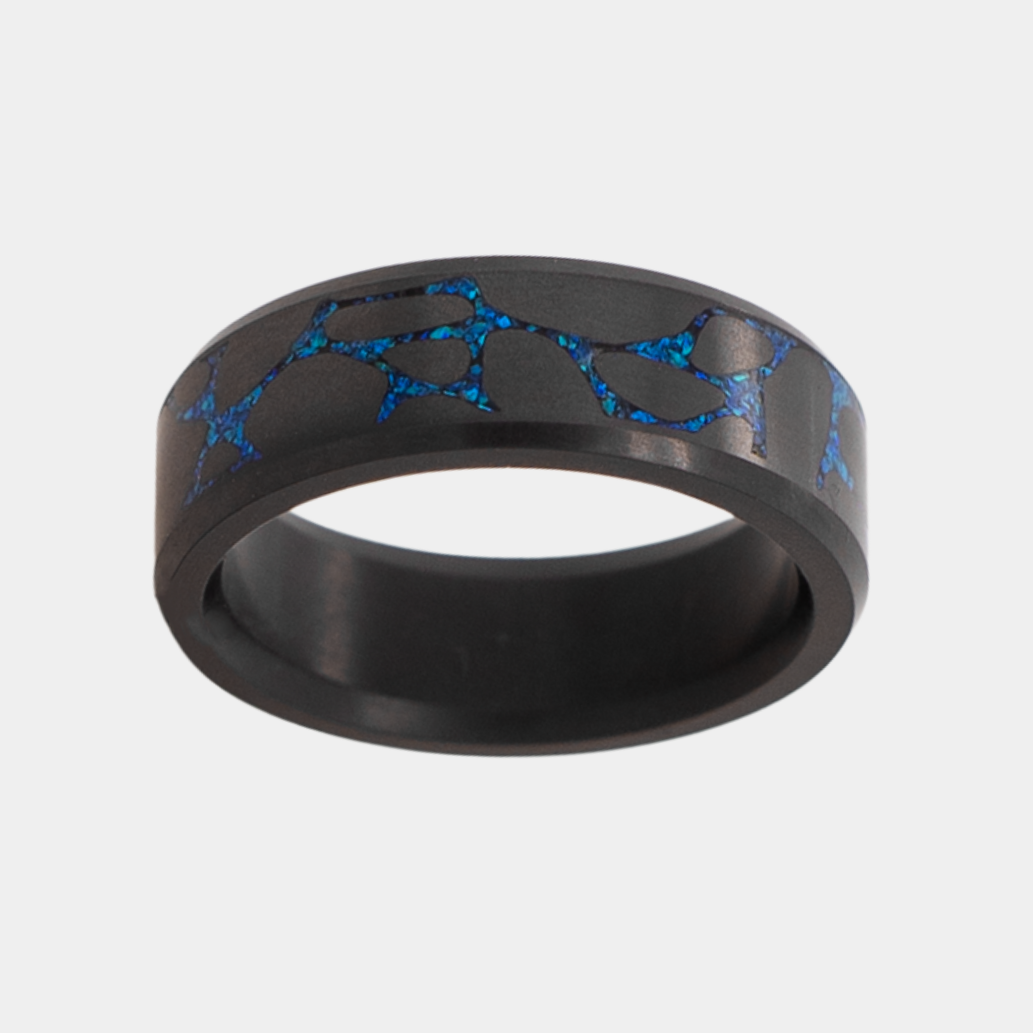 Top view of Solid Black Diamond ring with laser engraved river stone inlay filled with blue opal on a light gray background