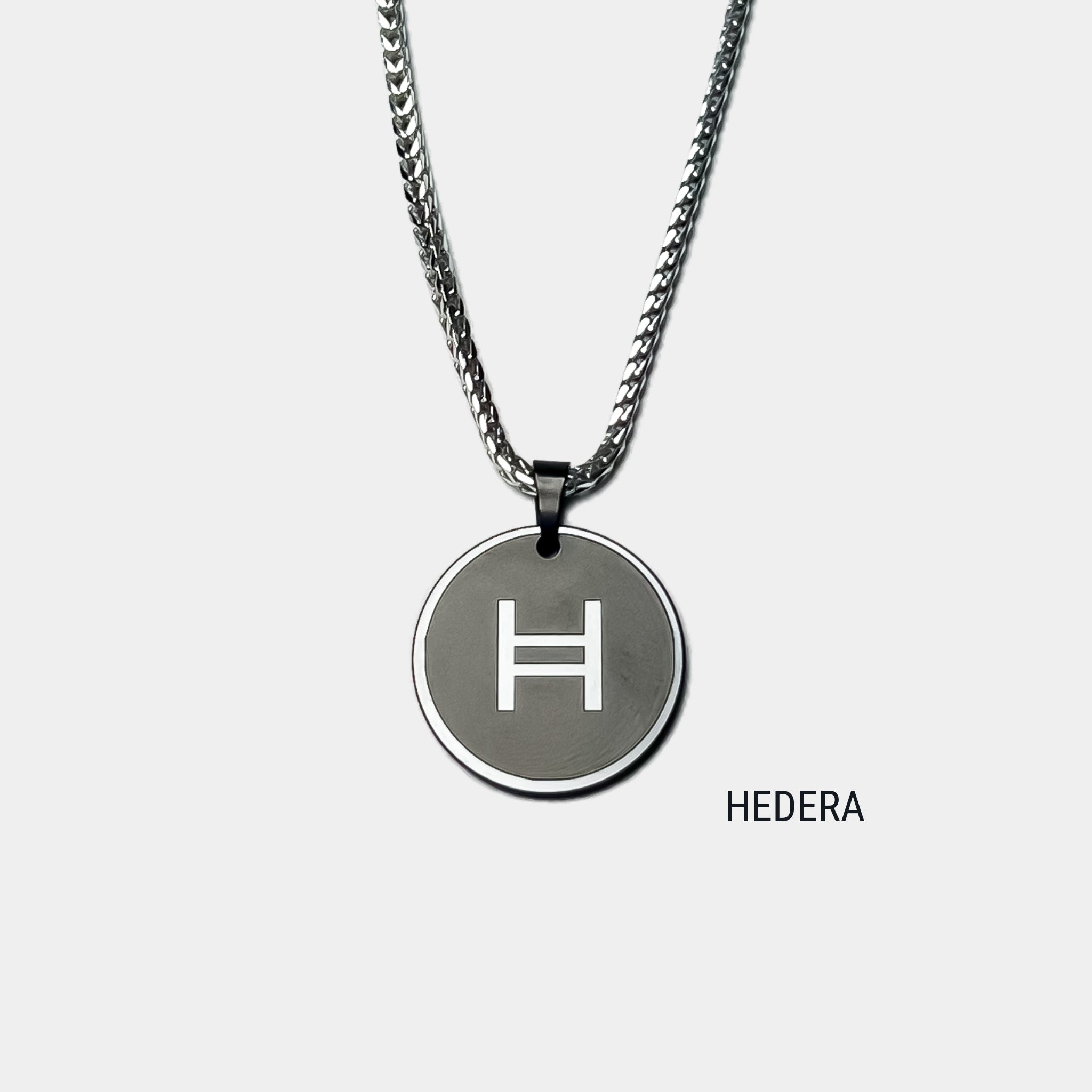 Photo of round solid black diamond pendant with hedera symbol engraved, attached to silver chain